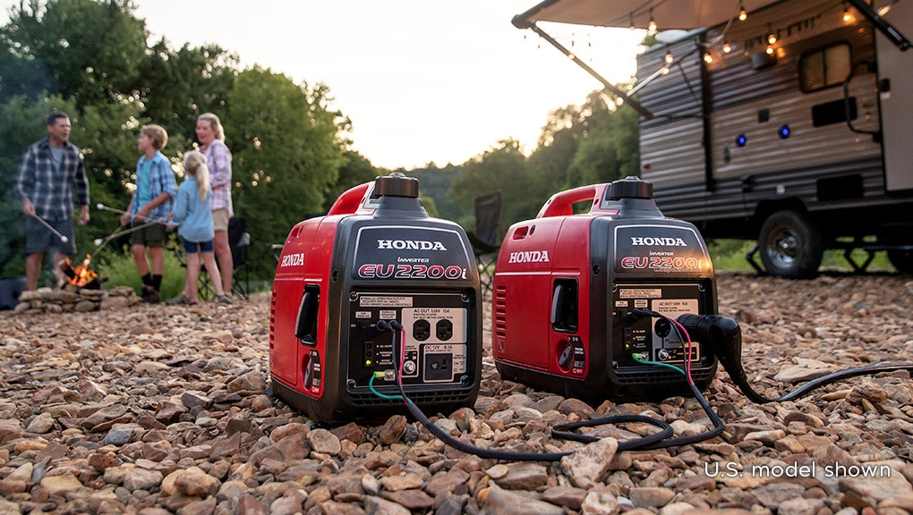 Close up image of generator in foreground with man in wooded campsite in background.