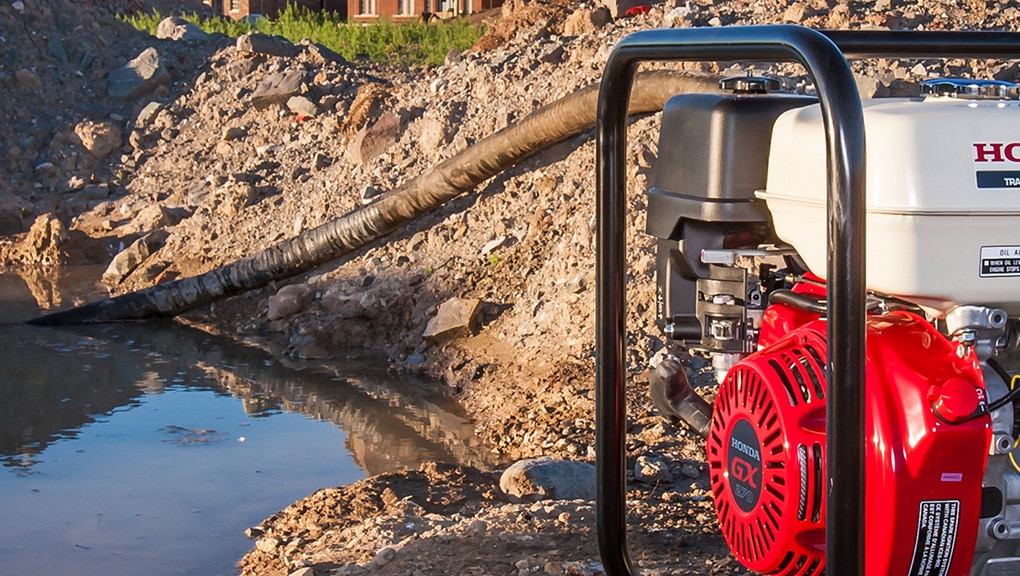 Close up of pump in foreground with hose attachment running to water in background