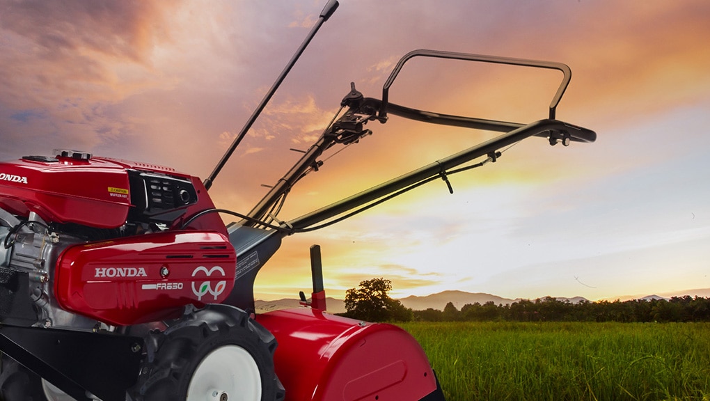 Close up of tiller in field with sunset in background